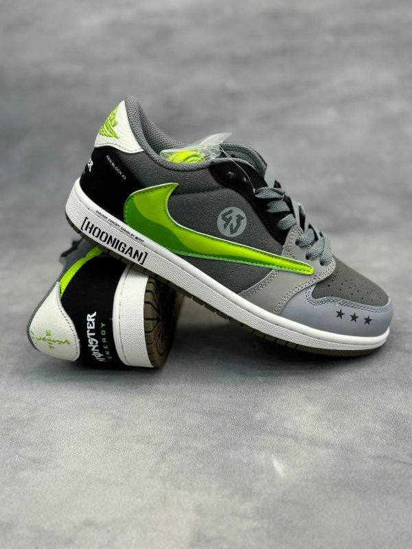 کتونی AJ1 Low Travis Scott x Hoonigan "Monster" با طراحی خاص، لوگوی سبز مانستر و ترکیب رنگ جذاب مشکی و سفید.