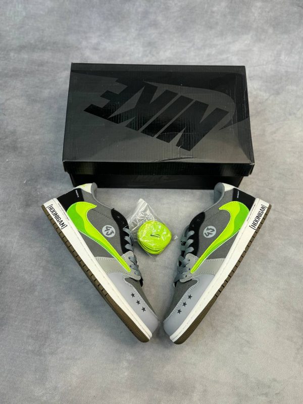 کتونی AJ1 Low Travis Scott x Hoonigan "Monster" با طراحی خاص، لوگوی سبز مانستر و ترکیب رنگ جذاب مشکی و سفید.